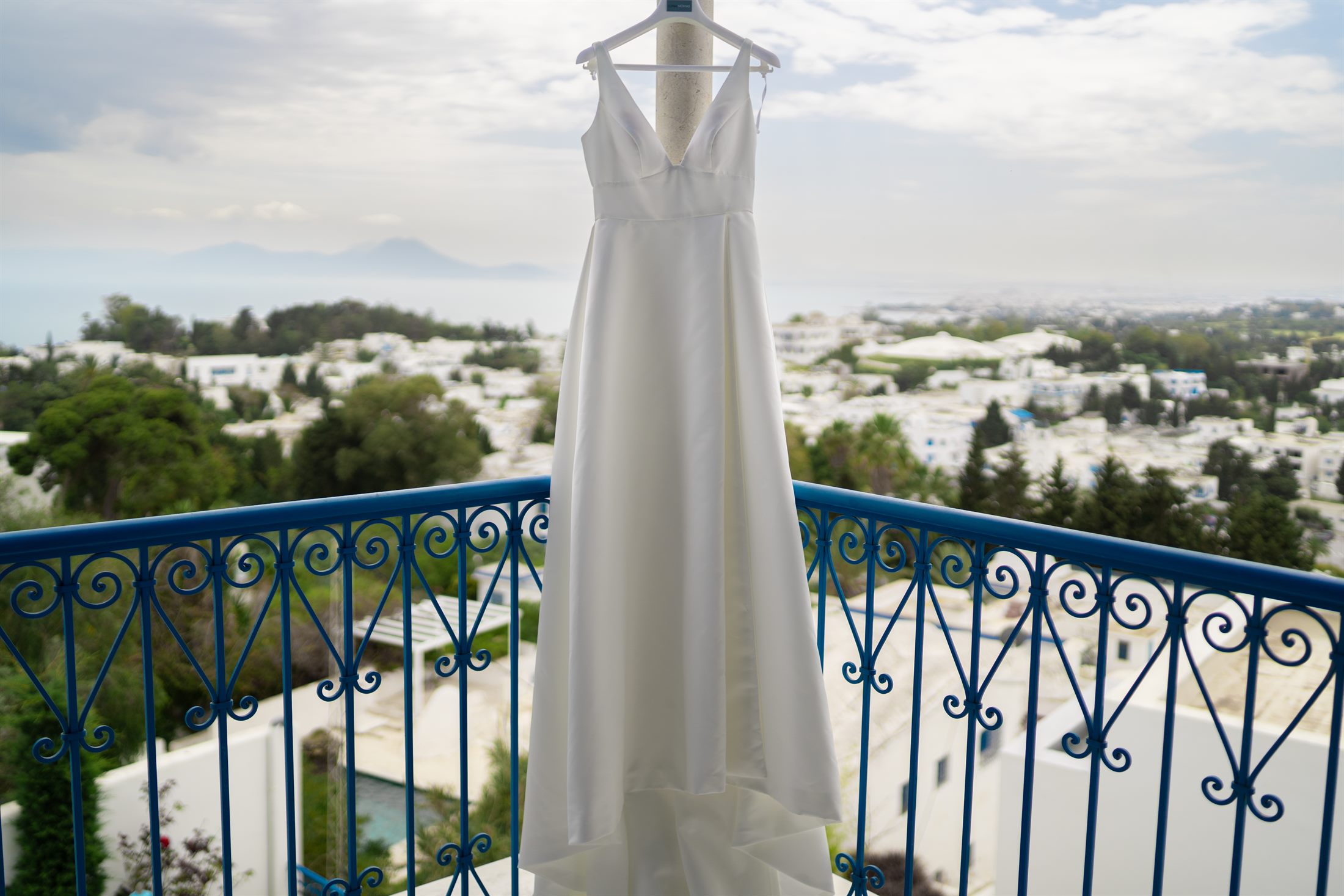 A wedding dress on a blue Tunisian balcony above white rooftops